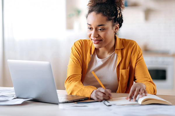 Woman with a pencil looking at a laptop